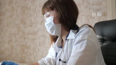 Teletıp, uzaktan tıbbi bakım kavramı. Beyaz önlüklü ve güvenlik gözlüklü kadın doktor dizüstü bilgisayar, online danışma ve konferans üzerinde çalışıyor. Doktor sanal kullanarak bir istemciyle iletişim kurar