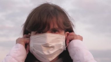 Koruyucu maskeli sağlıklı bir kız. Gün batımında koruyucu bir maske takan özgür bir kadın. Virüs ve bakterilere karşı koruma. Sağlık ve güvenlik konsepti, koronavirüs N1H1, koruma.