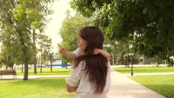 Mooie moeder draagt een dochtertje in het park in de open lucht. Mooie moeder en haar baby spelen in het park. baby en knuffelt gelukkige moeder. Gelukkige Moederdag Vreugde. Mam en baby. 4K — Stockvideo