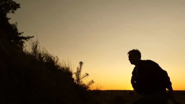 Concept of family adventure and travel. Free tourist traveler holds out his hand to a woman climbing to the top of the hill. teamwork travelers. Tourists climb the mountain at sunset, holding hands. — Stock Video