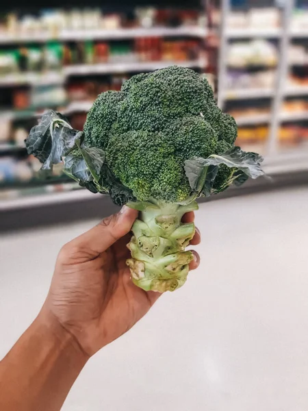 Mão Esquerda Segurando Brócolis Brócolis Fresco Uma Pilha Supermercado Brócolis — Fotografia de Stock