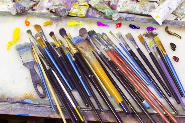 many art brushes lie on the palette, colored paints