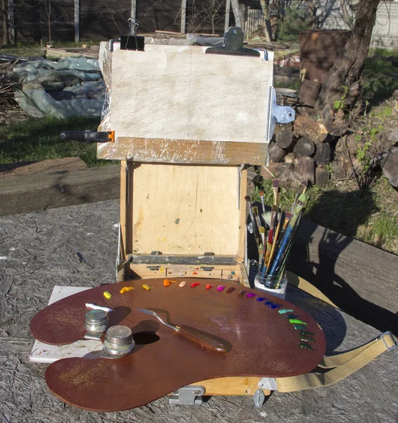 Plein air Etude Sketchbook for paintings. A palette with multicolored paints and palette knife lies on palette. White canvas for text, image. Plenary, creativity, hobby, inspiration, harmony.