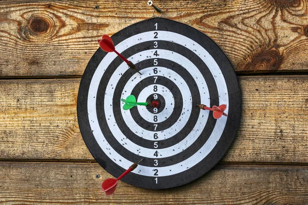 Darts. Old worn dart board with old darts on an old wooden wall