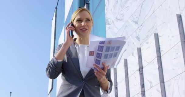 Бізнес-леді говорить по телефону і тримає документи — стокове відео