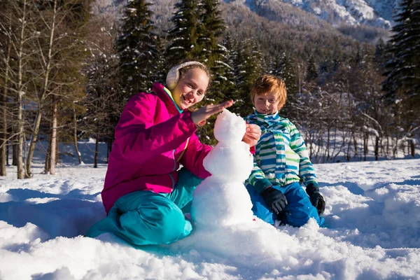 Brother Sister Building Snowman Together – stockfoto