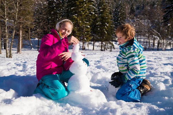 Siblings Building Snowman Together Sunny Day Royalty Free Stock Images