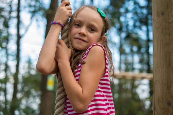 Ευτυχισμένο Κορίτσι Σκαρφαλώνει Ένα Σχοινί Στο Πάρκο Του Δάσους Φωτογραφία Αρχείου