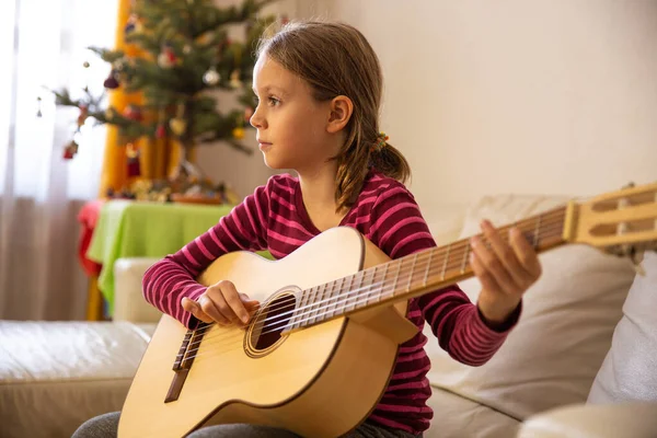 Küçük kız gitar çalmayı öğreniyor.