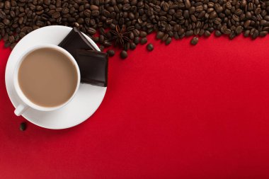 Coffee beans are scattered on a red paper background and a white