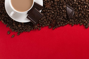 Coffee beans are scattered on a red paper background and a white