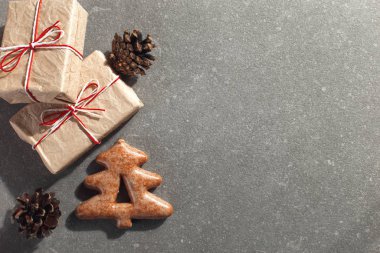 Christmas gingerbread cookies in the shape of a Christmas tree and craft gifts on a stone background, copy space.