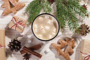 Hot Christmas drink with marshmallows in an iron mug and gingerbread cookies, on a white table. New Year, holiday background, greeting card copy space.