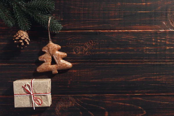 Galletas de jengibre de Navidad y ramas de pino y conos sobre un fondo de madera, espacio para copiar . — Foto de Stock