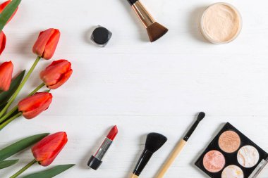 Beyaz masada kırmızı laleler ve kozmetik ürünler, boş. Boşluğu kopyala.
