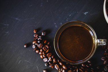 Kavrulmuş kahve çekirdeği ile sıcak espresso içki koyu arka plan üzerinde beyaz Kupası'nda. Yukarıdaki anahtar, Vintage sesi, düşük