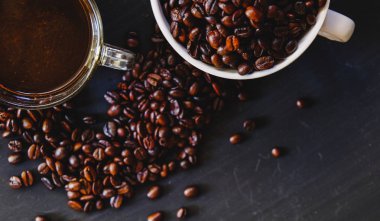 Kavrulmuş kahve çekirdeği ile sıcak espresso içki koyu arka plan üzerinde beyaz Kupası'nda. Yukarıdaki anahtar, Vintage sesi, düşük