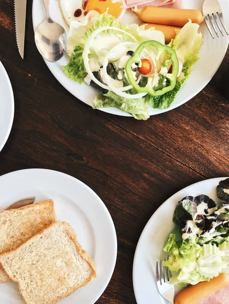 Otel kahvaltı - yumuşak haşlanmış pirinç kızarmış yumurta, pastırma, sosis, jambon, taze salata, genel gider görünümünü tost ve sıcak çay üstte ahşap bir masa