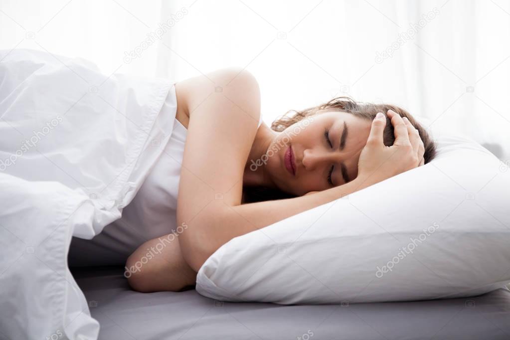 Young beautiful Caucasian woman on bed having headache / insomnia / migraine / stress