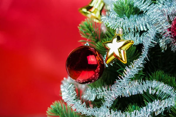 Close-up van kerstboom versierd met ornamenten in rijke glanzende rode achtergrond - met copyspace. — Stockfoto