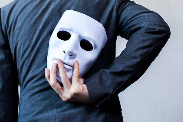 Business man carrying white mask to his body indicating Business fraud and faking business partnership.