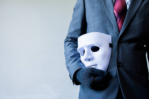Business man carrying white mask to his body indicating Business fraud and faking business partnership.