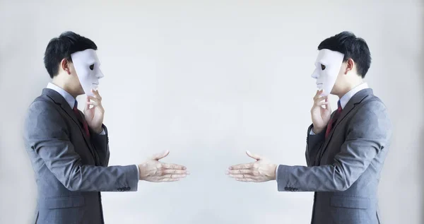 Two men in business suit handshaking with masks on - Business fraud and hypocrite agreement. Stock Image