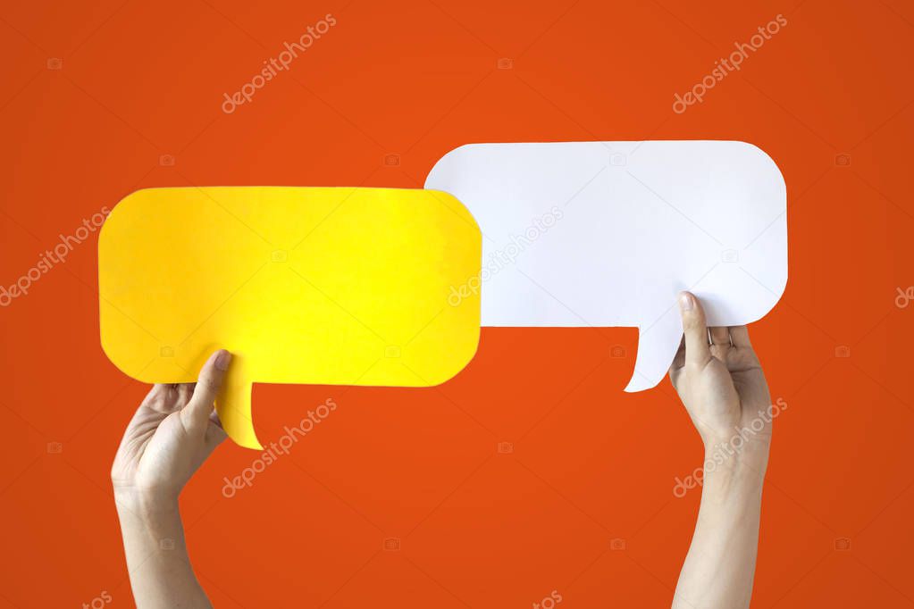 Human Hands Holding Yellow and White Speech Bubbles Over Orange Background