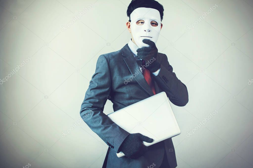 Business man in white mask wearing gloves and stealing computer and digital information - fraud, hacker, theft, cyber crime concept.