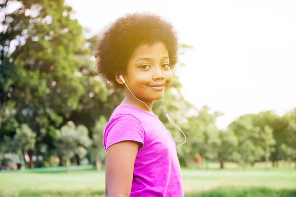 Niño sonriendo y escuchando música en el parque verde — Foto de Stock