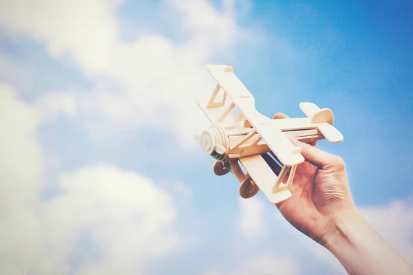 Ανθρώπινα χέρια κρατώντας ένα ξύλινο αεροπλάνο παιχνίδι πάνω από το γαλάζιο του ουρανού με copyspace — Φωτογραφία Αρχείου