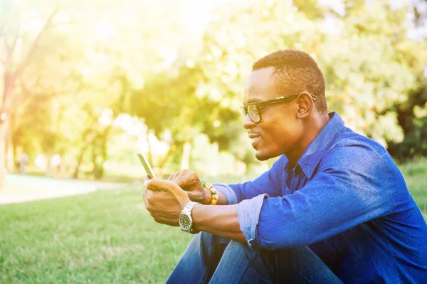 아프리카계 미국인 남자는 공원에서 휴대 전화를 사용 하 여 — 스톡 사진
