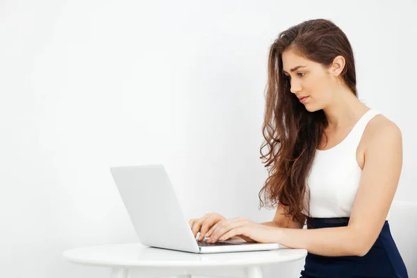 Beautiful Caucasian woman working on laptop on white desk over white isolated background with copy space — Stock Photo, Image