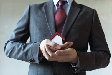 İş adamı kapsayan ve ev - koruma ellerini iş mortgage, Emlak kredi, ev sigortası, iş yatırım kavramı kullanarak takım elbiseli.