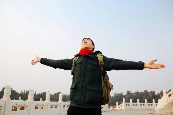Asian man stretching arms wide open in Chinese architecture with blue sky and copy space — Stock Photo, Image
