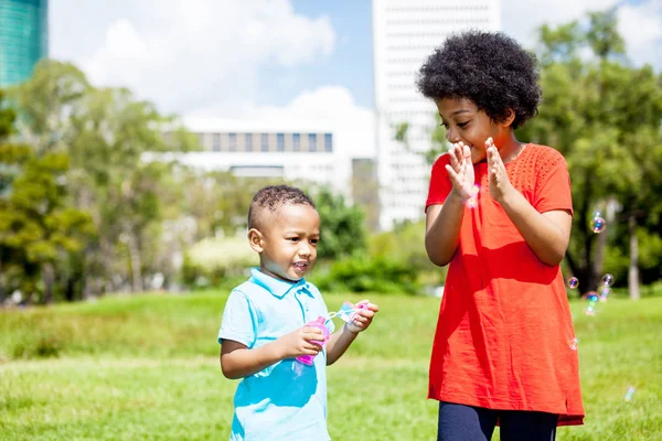 Feliz hermano y hermana soplando burbujas y jugando juntos — Foto de Stock