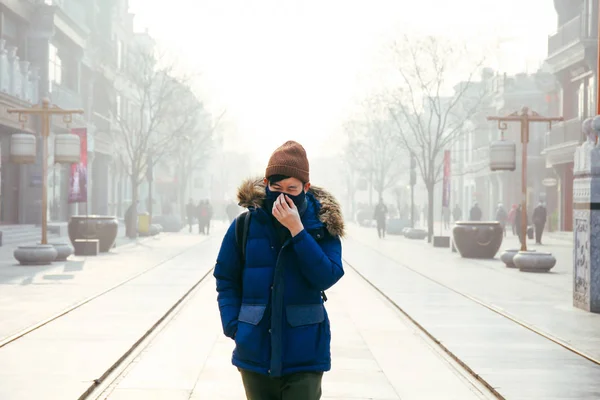 Hombre asiático caminando y usando una máscara facial en un niebla smog y nebuloso día como él sufre de severa contaminación del aire en Beijing, China —  Fotos de Stock
