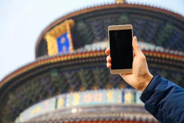 中国の寺院の背景にスマート フォンを使用している人のクローズ アップ — ストック写真