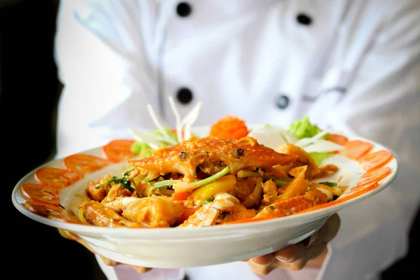 Chef proudly presenting Curry Crab with Coconut in dark dramatic background