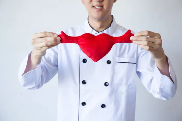 Happy smiling chef holding heart shape with love and passion