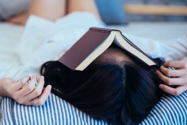 Kadın genç yüzü üstüne kitap - okurken uykuya dalar