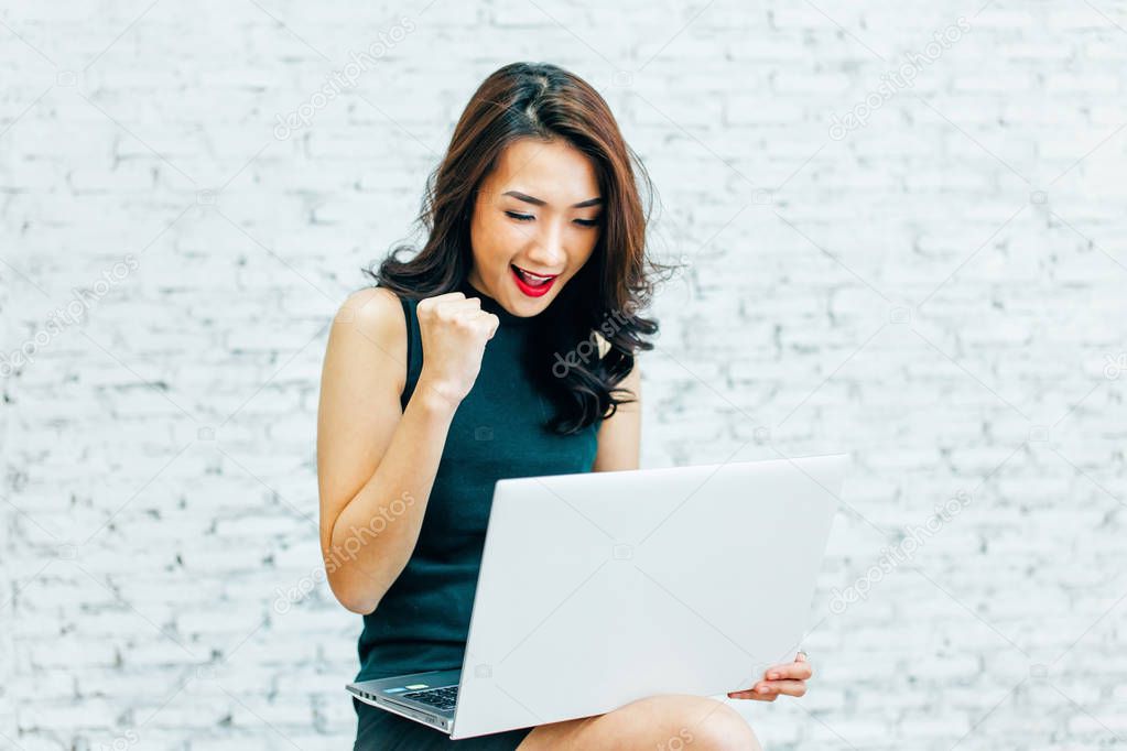 Young Asian business working woman winning and having success with laptop
