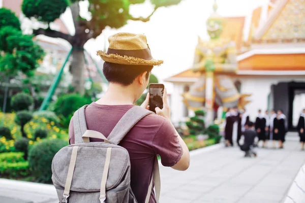 Joven asiático viajando mochilero tomar fotos con el teléfono inteligente i —  Fotos de Stock