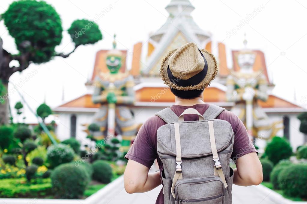 Young Asian traveling backpacker in Wat Arun with giant statues 