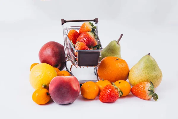 En kundvagn full av olika sorters frukt och matvaror isolerade över vit bakgrund — Stockfoto