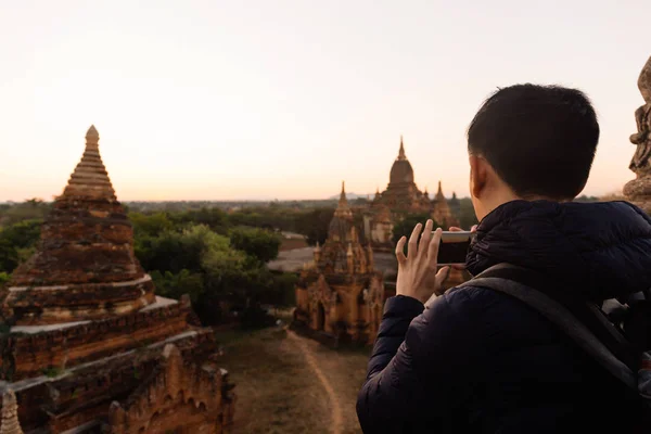 Jovem tirando uma foto com telefone celular na cena stupa do templo atrás em Bagan, Myanmar — Fotografia de Stock