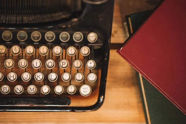 Old and vintage type writer machine and piles of books on wooden table - in vintage tone — Stock Photo, Image