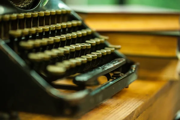 Old and vintage type writer machine and piles of books on wooden table - very selective focus — Stock Photo, Image