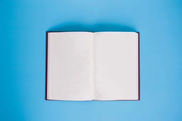 Libro abierto con páginas en blanco sobre fondo azul brillante - con espacio de copia — Foto de Stock