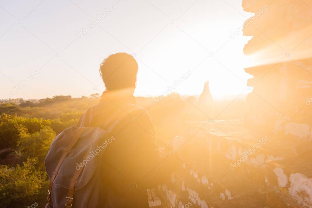 Silhouette of young male backpacker watching sunset and pagoda in Bagan, Burma